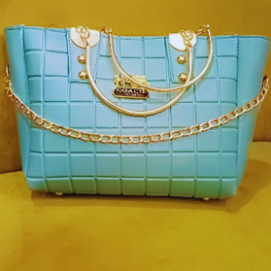 Turquoise quilted handbag with gold chain accents placed on a yellow background